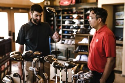 man standing beside man holding gray golf club