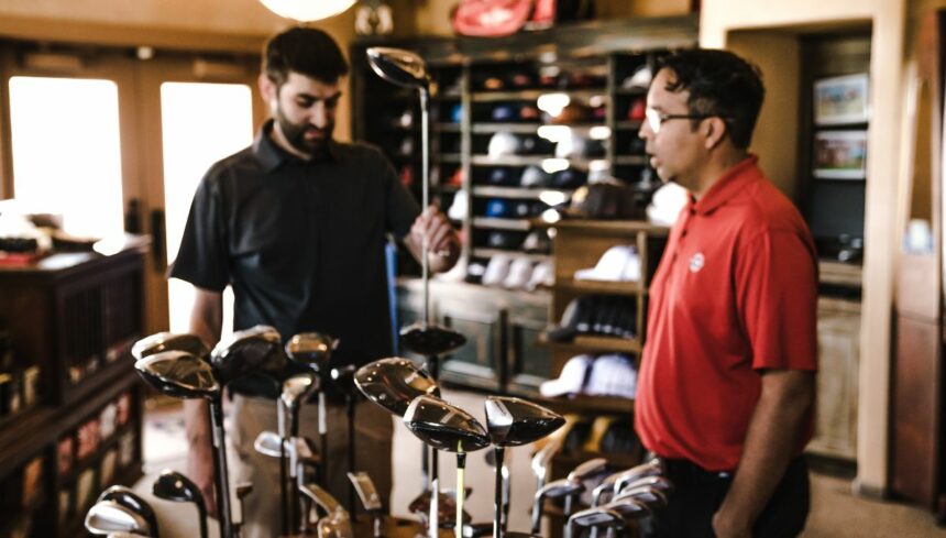 man standing beside man holding gray golf club